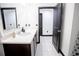 Bright bathroom featuring a modern vanity with a white countertop, dark cabinets, white tiled floors, and black trim at 13851 Rushing Creek Run, Orlando, FL 32824