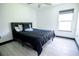 Sleek bedroom with modern black platform bed, stylish bedding, tiled floors, and a bright window at 13851 Rushing Creek Run, Orlando, FL 32824