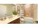 Bathroom featuring granite counters, dark cabinets, tiled shower/tub, and neutral tile floors at 206 Yellow Snapdragon Dr, Davenport, FL 33837