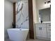 Modern bathroom featuring soaking tub, marble accent wall, and vanity with storage at 2336 Sw 168Th Loop, Ocala, FL 34473