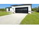 Modern home featuring a black garage door, sleek white exterior and newly planted landscaping at 2336 Sw 168Th Loop, Ocala, FL 34473