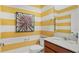 Stylish bathroom with a yellow and white striped wall, a vanity with a white countertop, and tiled floor at 2345 White Buffalo St, Apopka, FL 32703