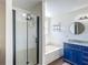 Bright bathroom with a glass-enclosed shower, soaking tub, blue double vanity, and modern fixtures at 3234 Amberley Park Cir, Kissimmee, FL 34743
