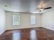 Spacious bedroom with sleek hardwood flooring, two windows with blinds, and a modern ceiling fan at 3234 Amberley Park Cir, Kissimmee, FL 34743