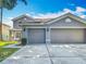 Exterior view showcasing an attached two-car garage with gray doors and well-kept driveway at 3234 Amberley Park Cir, Kissimmee, FL 34743