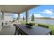 Covered patio with an outdoor dining set, overlooking a beautiful pond with lush green landscaping at 3326 Arch Ave, Ormond Beach, FL 32174