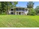 Backyard view of home featuring large lawn, mature trees, and screened in patio at 33925 Highland Rd, Leesburg, FL 34788