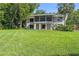 Backyard view of home featuring large lawn, mature trees, and screened in patio at 33925 Highland Rd, Leesburg, FL 34788