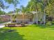 Two-story home with a well-manicured lawn, a red front door, and palm trees at 33925 Highland Rd, Leesburg, FL 34788