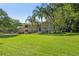 Charming two-story home with a sprawling green lawn and mature landscaping, including palm trees at 33925 Highland Rd, Leesburg, FL 34788
