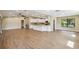 Spacious living area with wood flooring, a kitchen featuring white cabinetry, and large windows at 33925 Highland Rd, Leesburg, FL 34788