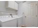Efficient laundry room with washer, dryer, storage shelving, and easy access door at 3539 Foxcroft Cir, Oviedo, FL 32765