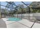 A screened-in pool with clear blue water, surrounded by a white concrete deck and lush greenery at 3539 Foxcroft Cir, Oviedo, FL 32765