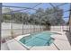 A screened-in pool with clear blue water, surrounded by a white concrete deck and lush greenery at 3539 Foxcroft Cir, Oviedo, FL 32765