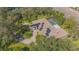 Aerial view of an expansive property featuring a solar paneled roof, screened-in pool, and circular driveway surrounded by trees at 4735 Chelsea Ct, Kissimmee, FL 34744
