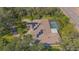 Aerial view of a sprawling home featuring solar panels, a screened-in pool, and a circular driveway amidst lush greenery at 4735 Chelsea Ct, Kissimmee, FL 34744