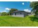 View of the backyard showcasing a gray home exterior, green lawn, and covered patio area for outdoor enjoyment at 506 Marion Oaks Trl, Ocala, FL 34473