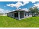 Rear view of the home with a covered patio overlooking a green, well-maintained lawn at 506 Marion Oaks Trl, Ocala, FL 34473