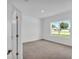 Bright bedroom with neutral carpet, white walls, and a large window offering natural light at 506 Marion Oaks Trl, Ocala, FL 34473