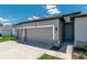 Attached three-car garage featuring gray doors, stone accents, and a teal front door at 506 Marion Oaks Trl, Ocala, FL 34473