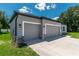 Attached three-car garage featuring gray doors, stone accents, and modern lighting fixtures at 506 Marion Oaks Trl, Ocala, FL 34473