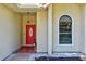 Close-up of the front door with red paint, an oval glass window, and a decorative light fixture at 602 Nighthawk Cir, Winter Springs, FL 32708