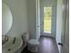 Comfortable half bathroom features wood-look vinyl floors and large round mirror at 706 Junonia Blvd, New Smyrna Beach, FL 32168