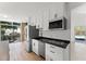 Open concept kitchen featuring white cabinets, laminate floors, stainless steel appliances, and an adjacent lounge space at 7712 Hoosier Pl, Orlando, FL 32807