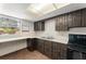 View of the kitchen, with dark wood cabinets and tiled floor, and an adjacent work space area at 7712 Hoosier Pl, Orlando, FL 32807
