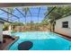The sparkling pool is surrounded by a screen enclosure, a stone waterfall, and mature landscaping at 7712 Hoosier Pl, Orlando, FL 32807