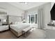 Bright main bedroom with a luxurious upholstered headboard, bench seating and large windows with decorative curtains at 7770 Sandy Ridge Dr # 234, Reunion, FL 34747