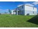 Backyard view of a two story home showcasing the patio, a large lawn, and sunny skies at 7779 Trapani Loop, Clermont, FL 34714