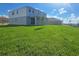 Wide shot of a lush green backyard with a two story house featuring large sliding glass doors at 7779 Trapani Loop, Clermont, FL 34714