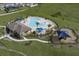 An aerial view of the community pool, splash pad, playground and picnic area on a green lawn at 7779 Trapani Loop, Clermont, FL 34714