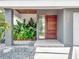 Modern home entrance featuring a wood door, stone walkway, and tropical landscaping at 8157 Elion St, Orlando, FL 32827