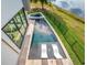 Aerial view of a modern pool with lounge chairs, spa, and lush green surroundings at 8157 Elion St, Orlando, FL 32827