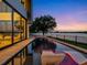 Modern home featuring a luxurious pool with in-water loungers overlooking a serene lake at twilight at 8157 Elion St, Orlando, FL 32827