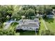 Aerial view of a property featuring a screened-in pool, mature trees, and well-kept lawn at 100 Demens St, Oakland, FL 34760