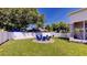 Backyard features a circle of blue chairs on brick, surrounded by well-manicured lawn and a white fence at 100 Demens St, Oakland, FL 34760