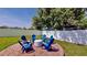 Outdoor firepit on a paver patio with six Adirondack chairs, all surrounded by white fence at 100 Demens St, Oakland, FL 34760