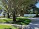 Scenic front yard view with mature trees, landscaping, and a circular driveway leading to the house at 100 Demens St, Oakland, FL 34760