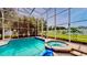Relaxing screened-in pool and spa area with lush greenery and blue accents at 100 Demens St, Oakland, FL 34760