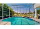 Inviting outdoor pool within a screened enclosure featuring an integrated spa and tropical landscaping at 100 Demens St, Oakland, FL 34760