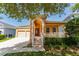 Inviting tan home with a striking arched entrance, two-car garage, and a cozy porch with white railing at 10076 Kimble Field Way, Orlando, FL 32827
