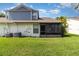 Back of home featuring a screened patio and green lawn under a sunny sky at 109 Lakepointe Cir, Kissimmee, FL 34743