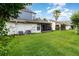 Green backyard lawn with view of home's rear exterior and screened patio at 109 Lakepointe Cir, Kissimmee, FL 34743