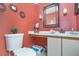Well-lit half bathroom featuring a decorative mirror and an orange painted accent wall at 109 Lakepointe Cir, Kissimmee, FL 34743