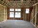 Spacious, light-filled living room in a home under construction with exposed beams and multiple windows for natural light at 15465 Hamlin Park Drive, Winter Garden, FL 34787