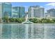 Picturesque view of the lake with a fountain, reflecting nearby buildings and greenery at 155 S Court Ave # 1909, Orlando, FL 32801