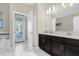 Bright bathroom with dual sinks, white tile flooring, and a door to the outside at 2927 Fable St, Kissimmee, FL 34746